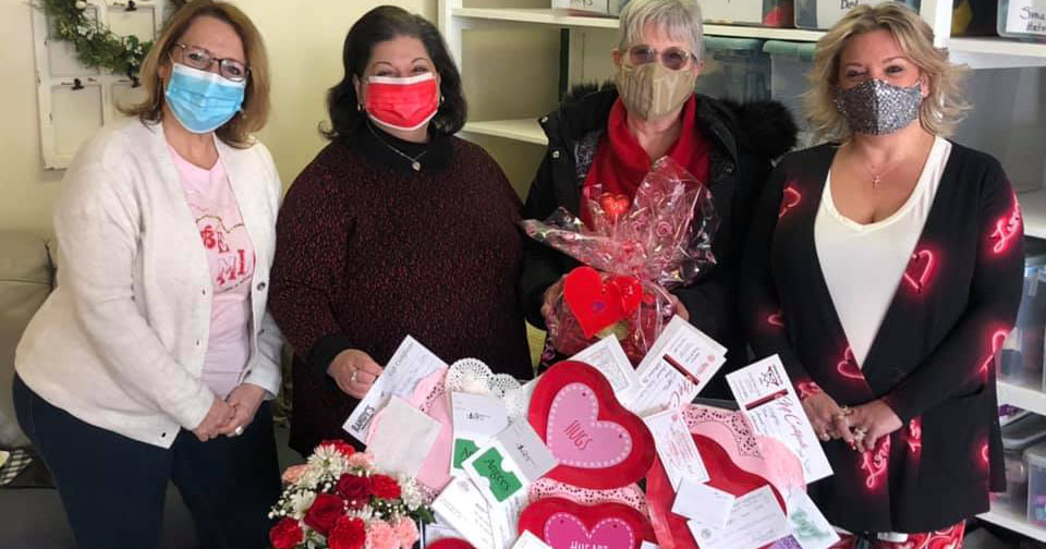 Operation Warm Hearts volunteers Ann Marie Sitter Tompkins (far left), Claudia Attard (middle left) and Pamela Shumway (far right) present a prize to a raffle winner, Mary Freeman (middle right).